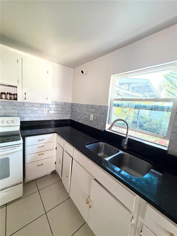 A kitchen features white cabinets, black countertops, a stainless steel sink, and light-colored tile flooring — 8904 N 20TH STREET, TAMPA, FL