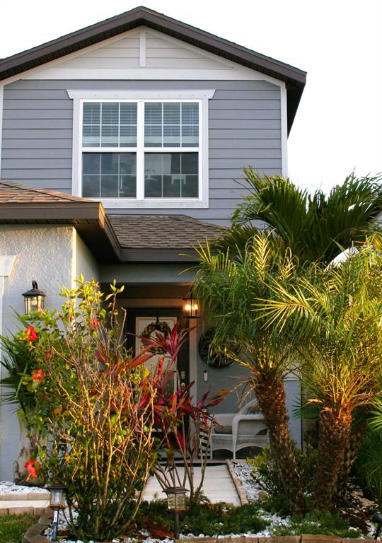 A two-story house with gray siding, a front porch, and landscaping featuring palm trees — 8323 REEFBAY COVE, PARRISH, FL