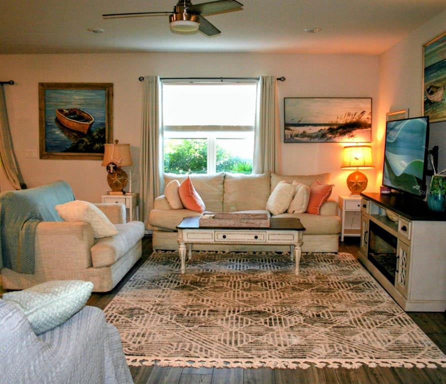 A living room features a beige sofa, patterned area rug, and a television on a console — 8323 REEFBAY COVE, PARRISH, FL