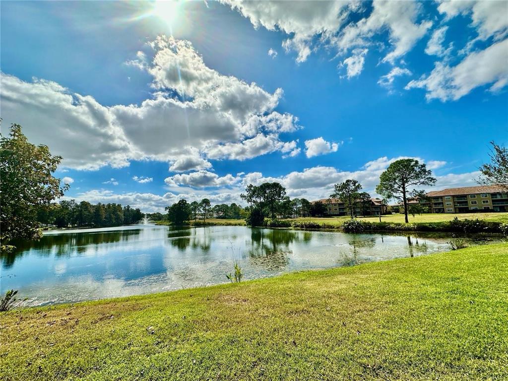 A grassy lawn overlooks a pond with a fountain and apartment buildings in the distance — 13536 TURTLE MARSH LOOP UNIT 532, ORLANDO, FL