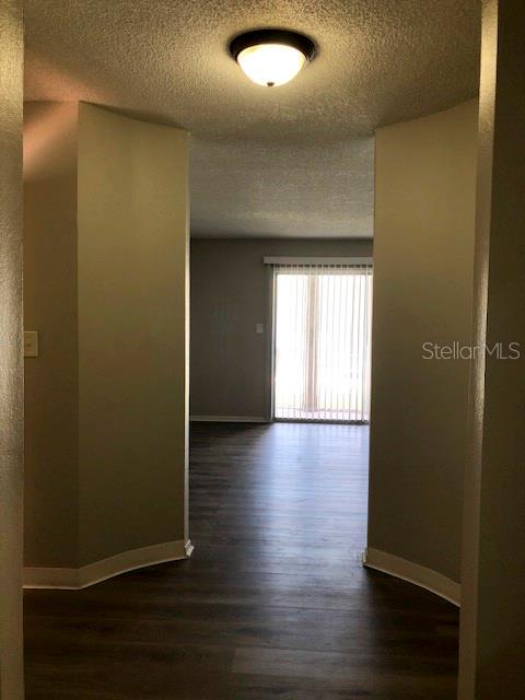 A hallway with wood-look flooring leads to a living area with a sliding glass door — 548 ORANGE DRIVE UNIT 14, ALTAMONTE SPRINGS, FL