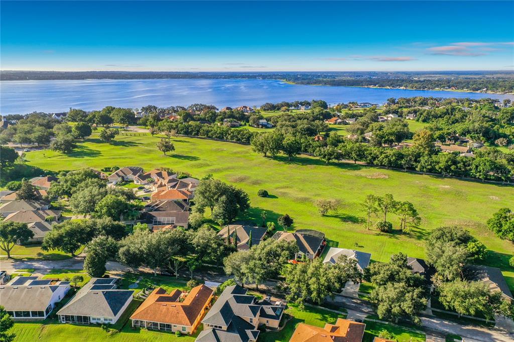 An aerial view of a residential neighborhood with houses, green lawns, and a large lake — 9833 SPRING LAKE DRIVE, CLERMONT, FL