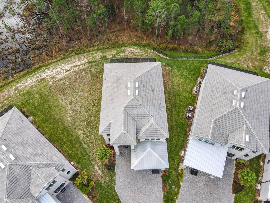 An aerial view shows three houses with gray tile roofs surrounded by lawns and trees — 2125 PINE OAK LOOP, DAVENPORT, FL