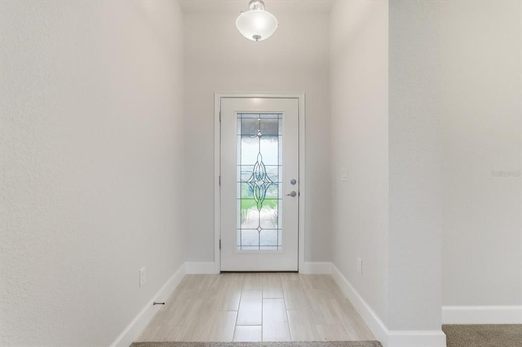 A bright entryway features light-colored tile flooring, white walls, and a glass-paneled front door — 336 W REXFORD DRIVE, BEVERLY HILLS, FL