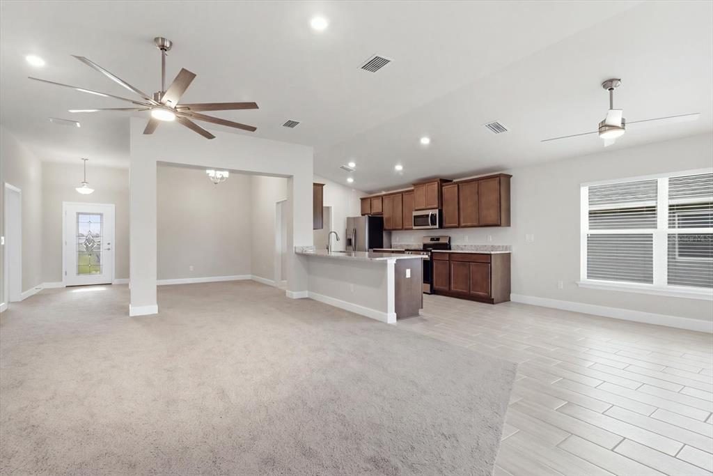 An open-concept living area features carpeted flooring, a kitchen with dark cabinets, and tile flooring — 336 W REXFORD DRIVE, BEVERLY HILLS, FL
