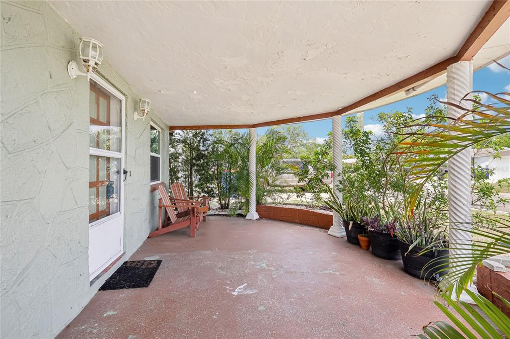A covered porch with a concrete floor, white columns, and two wooden chairs — 3548 DARLINGTON ROAD, HOLIDAY, FL