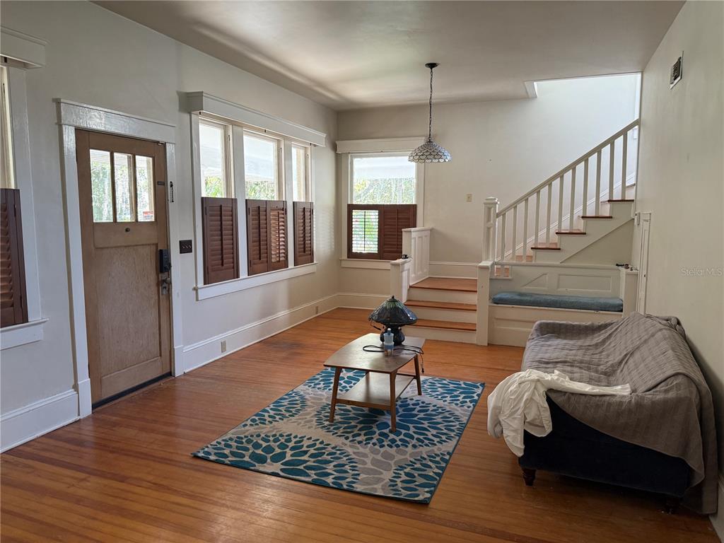 A living room features hardwood floors, a wooden front door, and a staircase with seating — 404 NE 10TH AVENUE, GAINESVILLE, FL