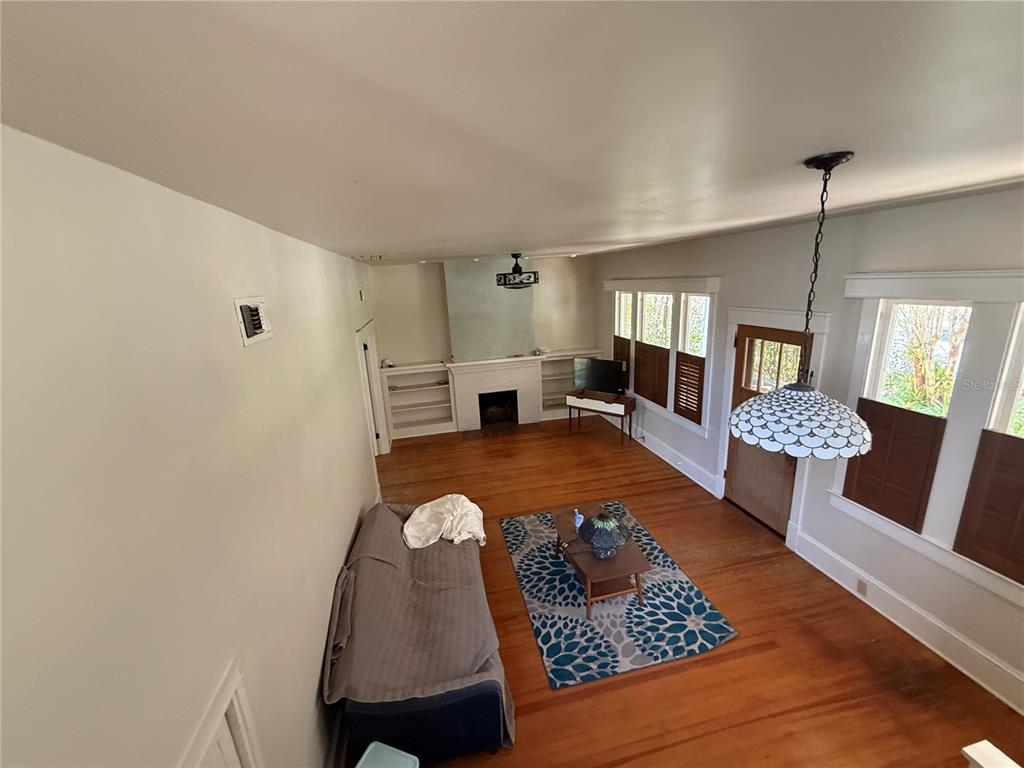 A living room features hardwood floors, a fireplace with built-in shelves, and a pendant light — 404 NE 10TH AVENUE, GAINESVILLE, FL