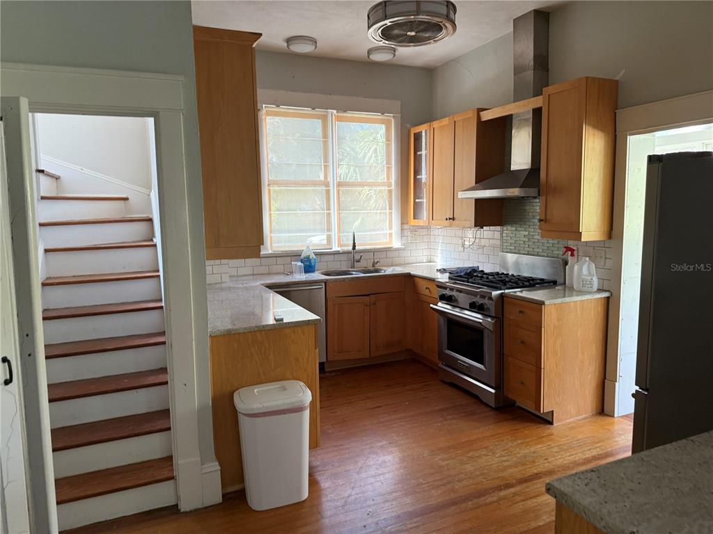 A kitchen with wooden cabinets, stainless steel appliances, and a staircase visible to the left — 404 NE 10TH AVENUE, GAINESVILLE, FL