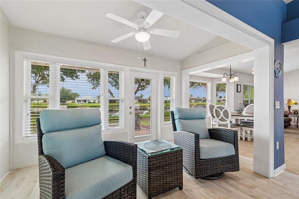 A sunroom with wicker chairs, a ceiling fan, and a view of a pond — 12133 ARRON TERRACE, TRINITY, FL