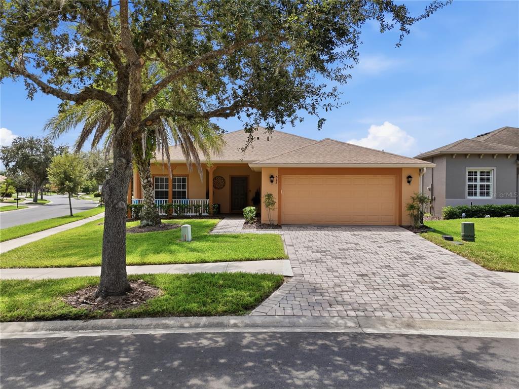 A single-story house with a tan exterior, a paved driveway, and a large front yard tree — 513 BARCELONA DRIVE, KISSIMMEE, FL