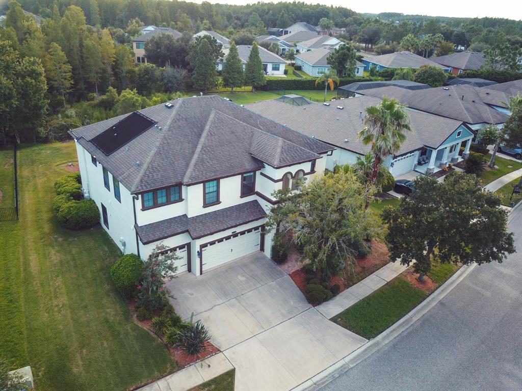 An aerial view shows a two-story suburban house with a dark roof and solar panels — 8355 SWISS CHARD CIRCLE, LAND O LAKES, FL
