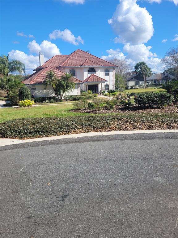 A two-story house with a red tile roof sits behind a landscaped front yard — 2701 REGAL POINT PLACE, EUSTIS, FL