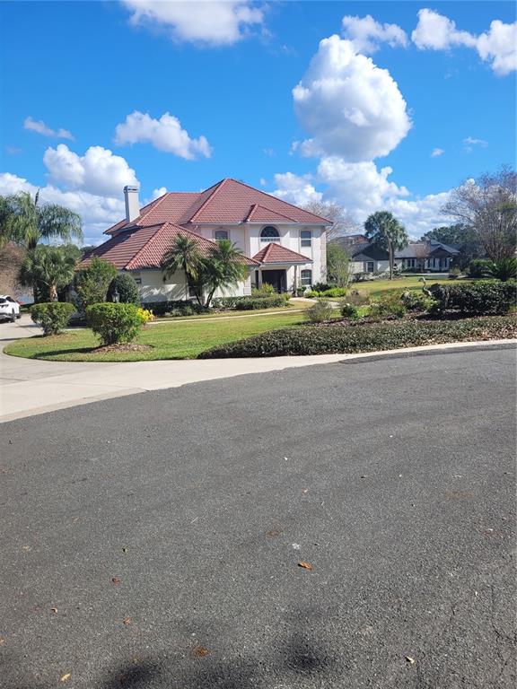 A two-story house with a red tile roof sits on a grassy lot — 2701 REGAL POINT PLACE, EUSTIS, FL