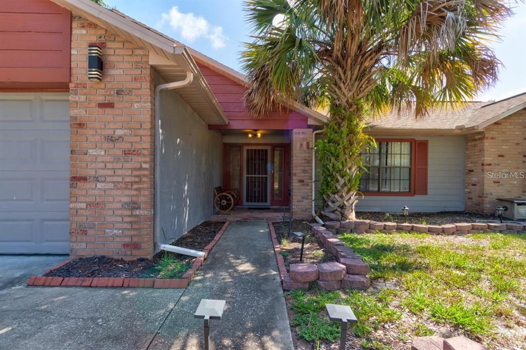 A brick and siding house exterior features a concrete walkway, a palm tree, and a garage — 3237 NEWMARK DRIVE, DELTONA, FL