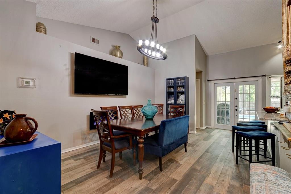 A dining room features a dark wood table, blue upholstered chairs, and a modern chandelier — 3237 NEWMARK DRIVE, DELTONA, FL
