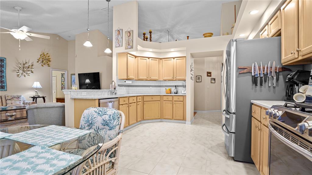 A kitchen with light wood cabinets, stainless steel appliances, and a dining area — 9221 HALBERG DRIVE, HUDSON, FL