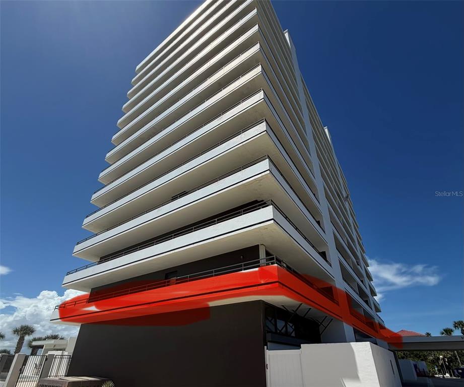 A low-angle exterior view of a modern high-rise apartment building with a red-highlighted section — 1601 N CENTRAL AVENUE UNIT 101, FLAGLER BEACH, FL