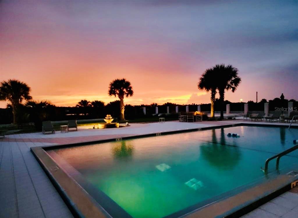 A swimming pool sits on a patio at sunset with palm trees and a fountain — 1601 N CENTRAL AVENUE UNIT 101, FLAGLER BEACH, FL