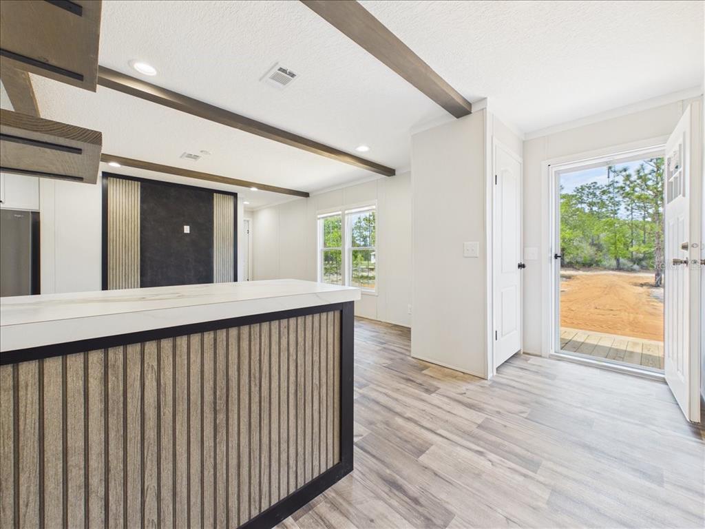 A kitchen island with wood-slat paneling faces an open living area with a glass exterior door — 202 MIMOSA DRIVE, HAWTHORNE, FL