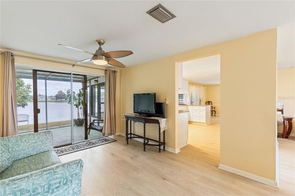 A living room with light wood flooring, a ceiling fan, and a view of water — 3228 ROCK VALLEY DRIVE, HOLIDAY, FL