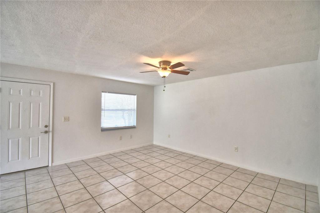 An empty room features white walls, a tiled floor, and a ceiling fan — 914 GRAPE AVENUE, ST CLOUD, FL