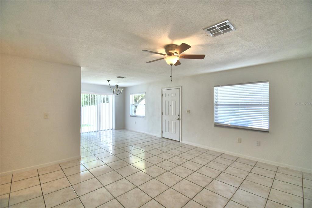 An empty living room features white walls, tile flooring, a ceiling fan, and a front door — 914 GRAPE AVENUE, ST CLOUD, FL