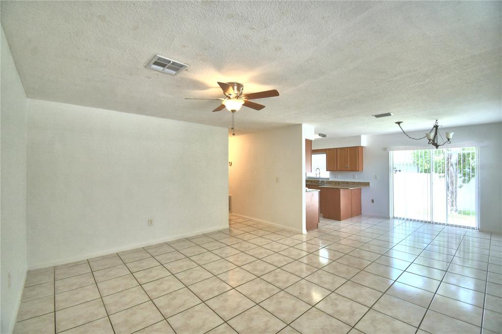 An open-concept living and dining area features light-colored floor tiles and a ceiling fan — 914 GRAPE AVENUE, ST CLOUD, FL
