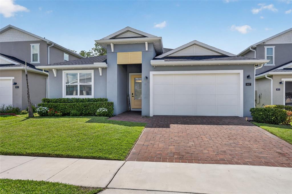 A single-story house with a gray stucco exterior, a brick driveway, and a white garage — 3607 ARBORDALE LOOP, SANFORD, FL