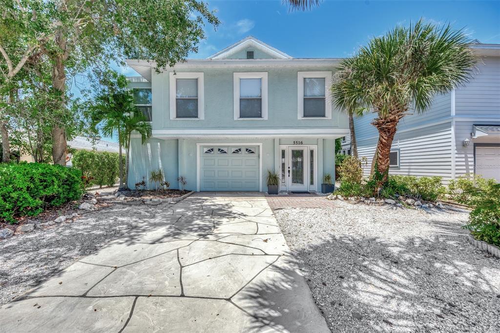 A two-story light blue house features a stone-patterned driveway and a palm tree — 5516 AVENIDA DEL MARE, SARASOTA, FL