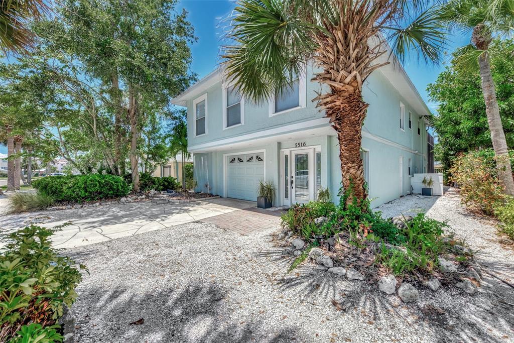 A light blue two-story house with a garage and palm trees in a gravel yard — 5516 AVENIDA DEL MARE, SARASOTA, FL