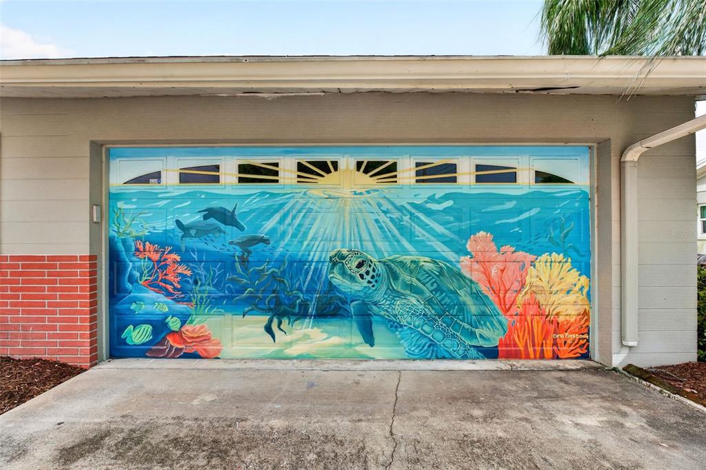 A garage door features a large, colorful mural of a sea turtle and coral reef — 3409 18TH AVENUE DRIVE W, BRADENTON, FL