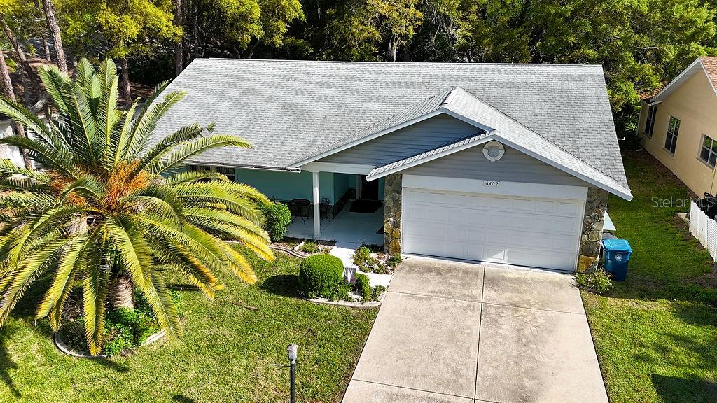 An aerial view of a single-story house with a gray roof, garage, and palm tree — 6402 OCEAN PINES LANE, SPRING HILL, FL