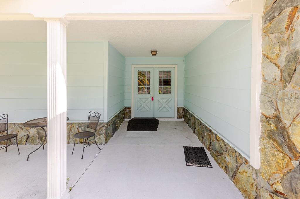 A covered porch features light blue walls, stone siding, and a double front door — 6402 OCEAN PINES LANE, SPRING HILL, FL