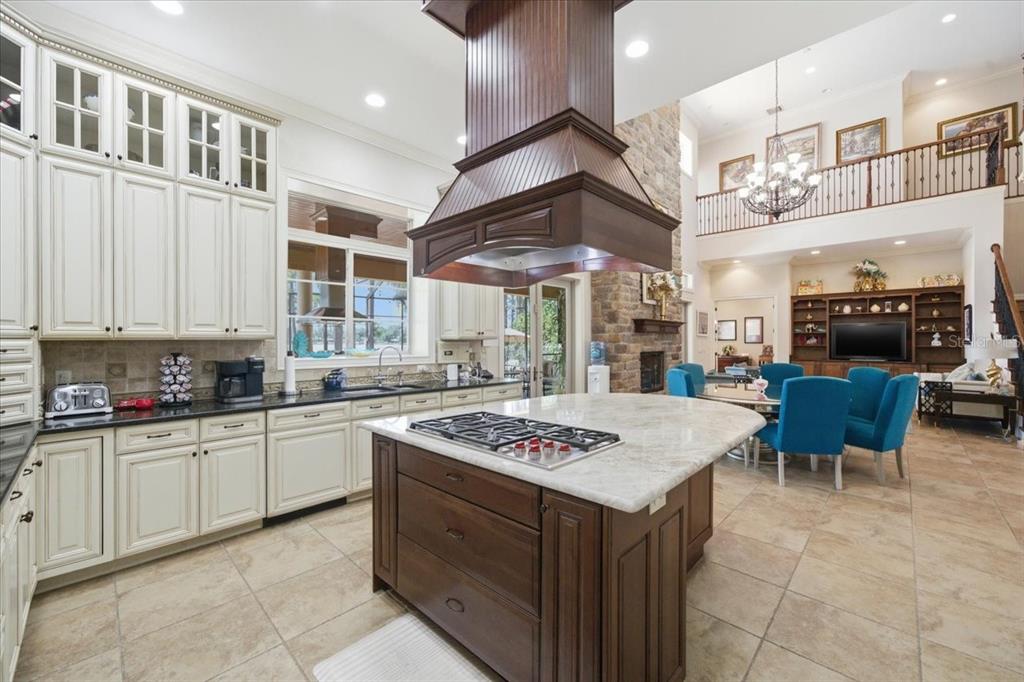 A kitchen with white cabinets, a dark wood island, and a stone fireplace in view — 18258 WAYNE ROAD, ODESSA, FL