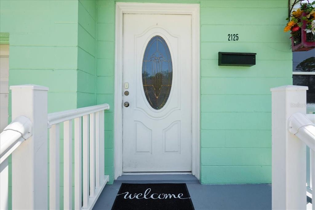 A white front door with an oval glass insert sits on a light green porch — 2125 W LOU DRIVE, JACKSONVILLE, FL