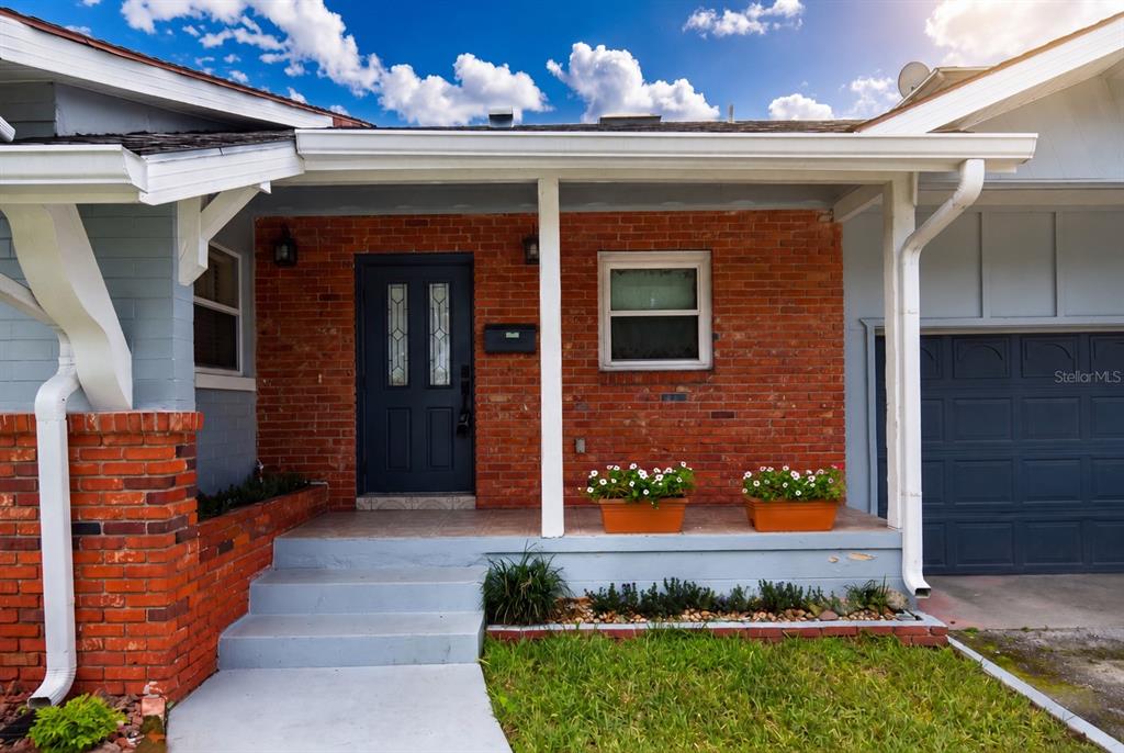 A brick-front house exterior features a covered porch, a dark front door, and a garage — 1540 E HORATIO AVENUE, MAITLAND, FL
