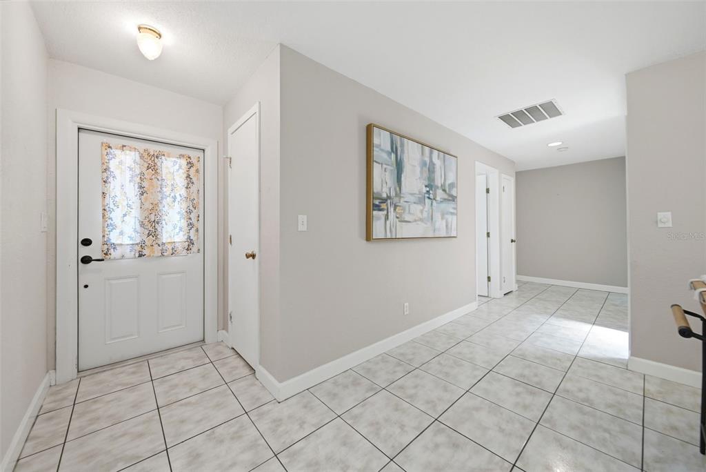 An entryway with white tile floors, a front door with a floral curtain, and light walls — 1540 E HORATIO AVENUE, MAITLAND, FL