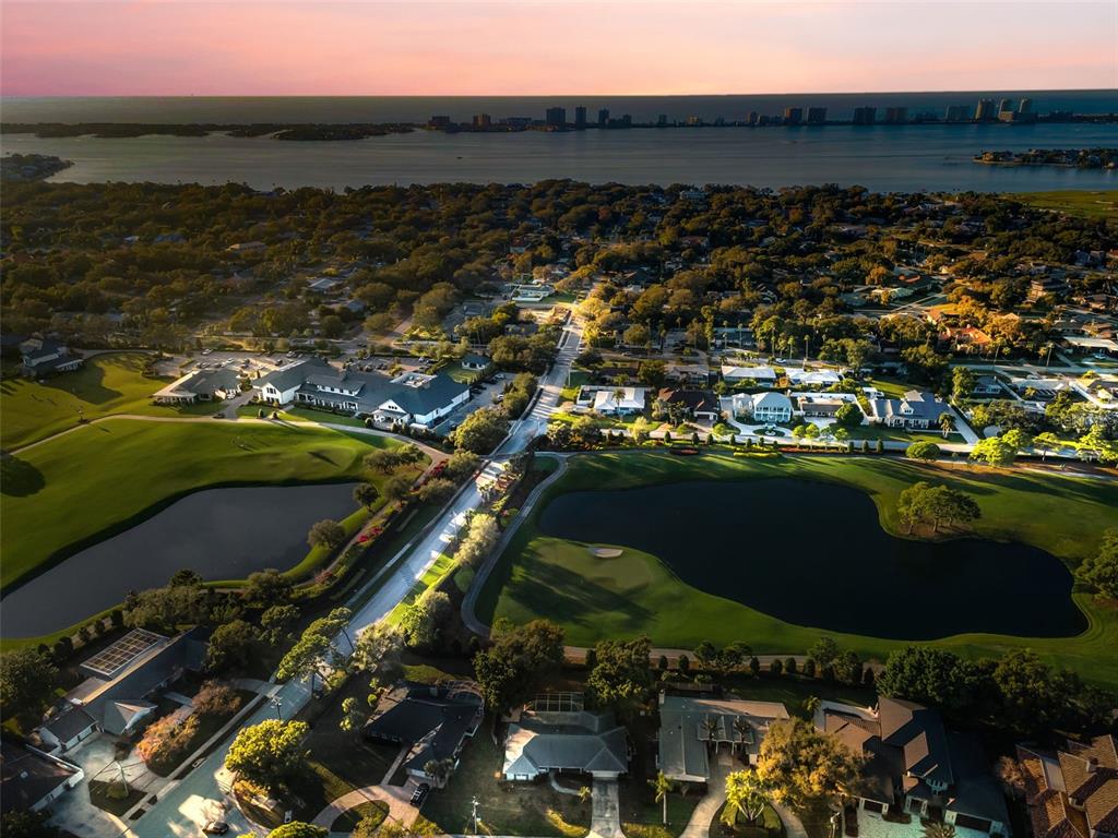 An aerial view shows a residential neighborhood surrounding a golf course with ponds at sunset — 4 HIBISCUS ROAD, BELLEAIR, FL
