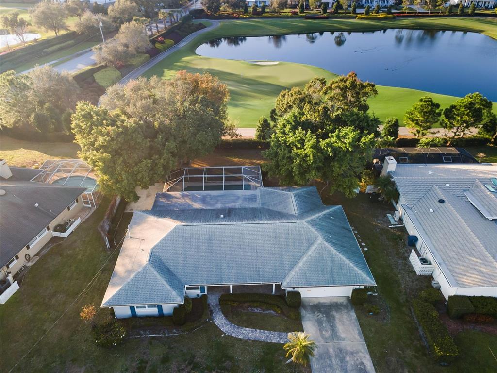 An aerial view shows a house with a pool cage overlooking a golf course pond — 4 HIBISCUS ROAD, BELLEAIR, FL