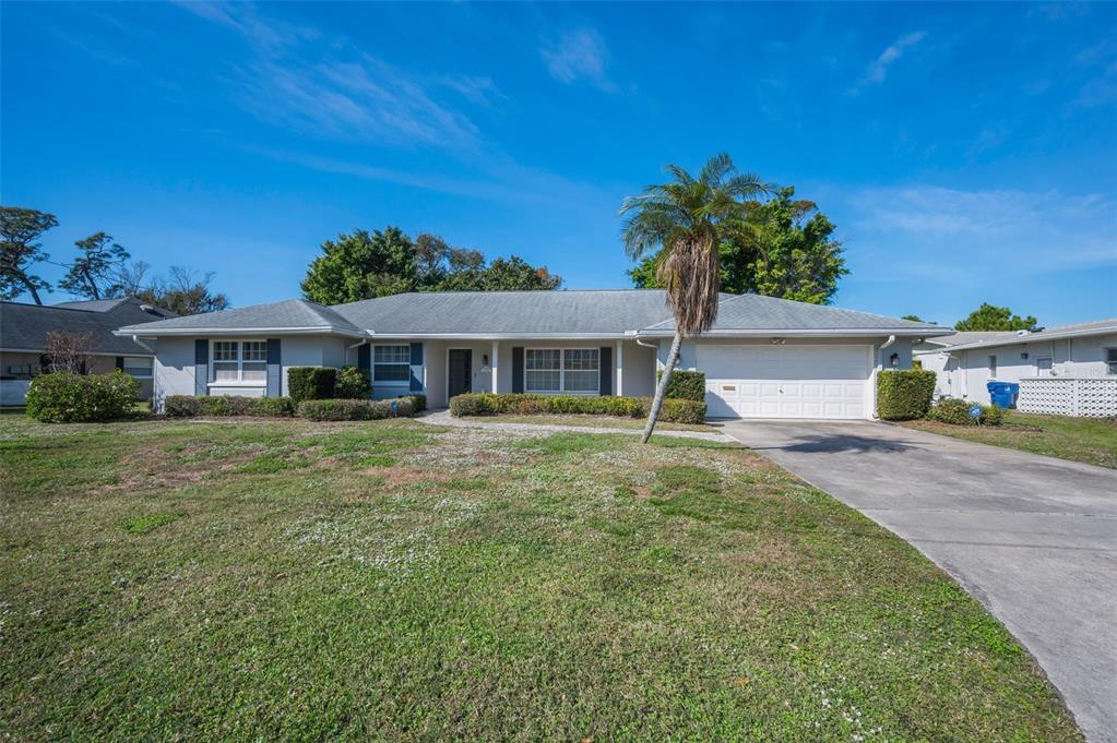 A single-story house with a gray roof, white garage door, and a palm tree — 4 HIBISCUS ROAD, BELLEAIR, FL