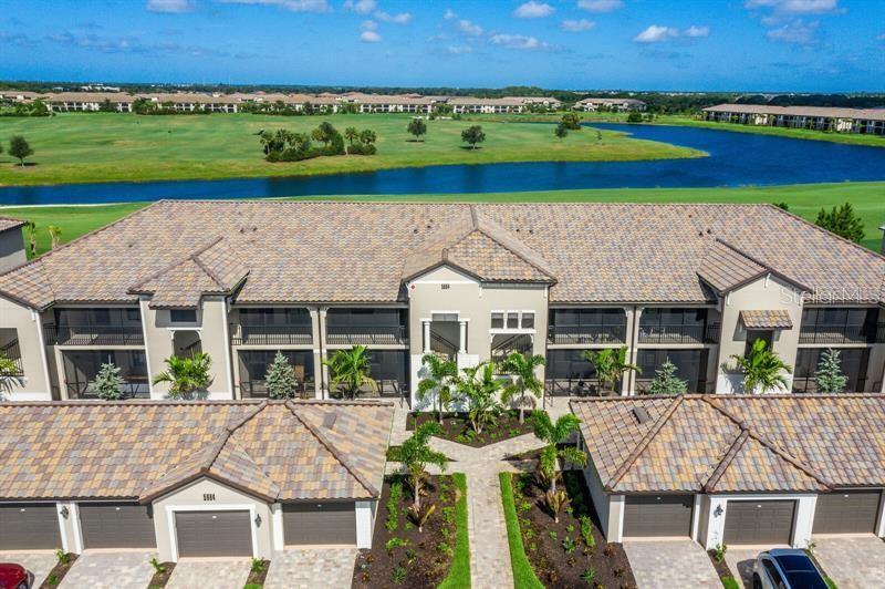 An aerial view shows a multi-story apartment building with attached garages and a golf course — 5664 PALMER CIRCLE UNIT 202, BRADENTON, FL