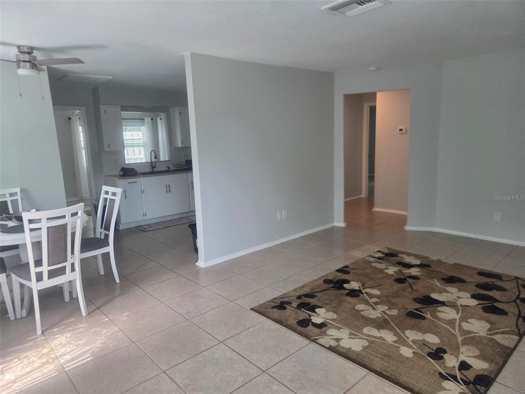 A dining area and living space with tile floors, white cabinets, and a floral rug — 865 7TH STREET S, SAFETY HARBOR, FL