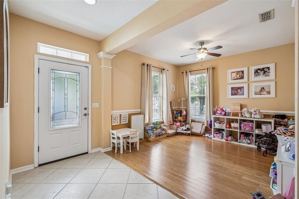 A bright entryway and playroom with tile and hardwood flooring, windows, and a ceiling fan — 206 NORFOLK PLACE, CELEBRATION, FL