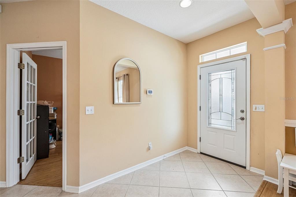 An entryway with beige walls, tile flooring, a white front door, and an arched mirror — 206 NORFOLK PLACE, CELEBRATION, FL