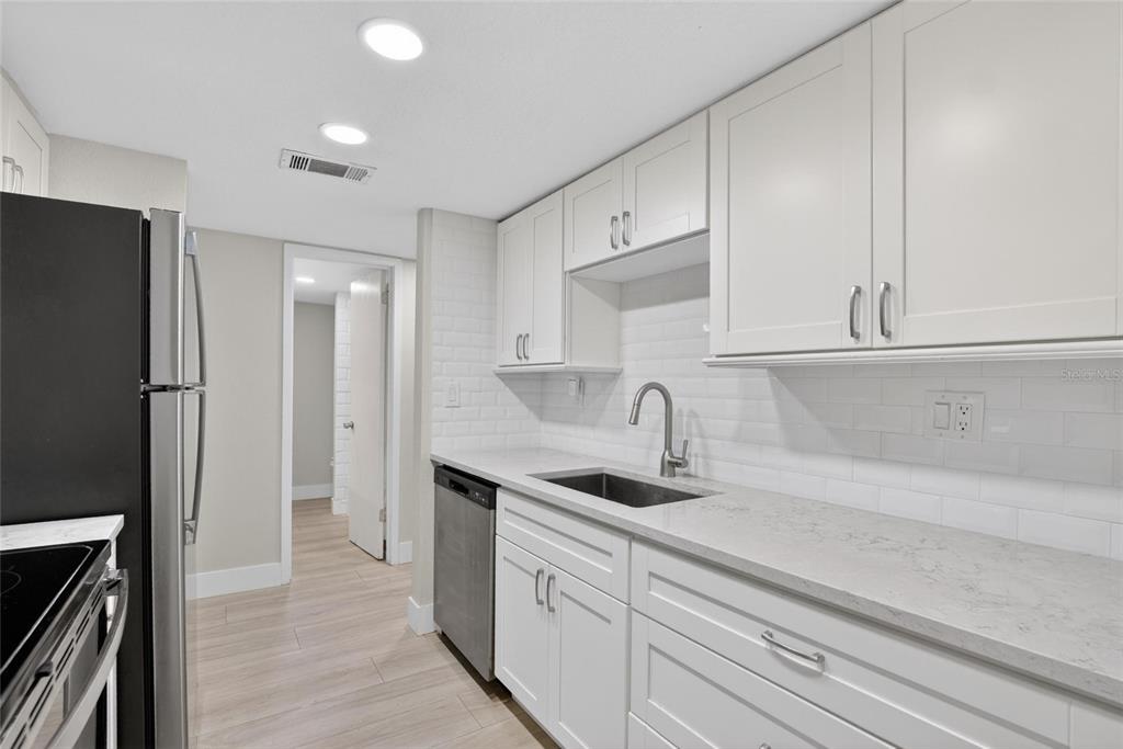 A kitchen features white shaker cabinets, light quartz countertops, a subway tile backsplash, and appliances — 3795 41ST LANE S UNIT A, ST PETERSBURG, FL