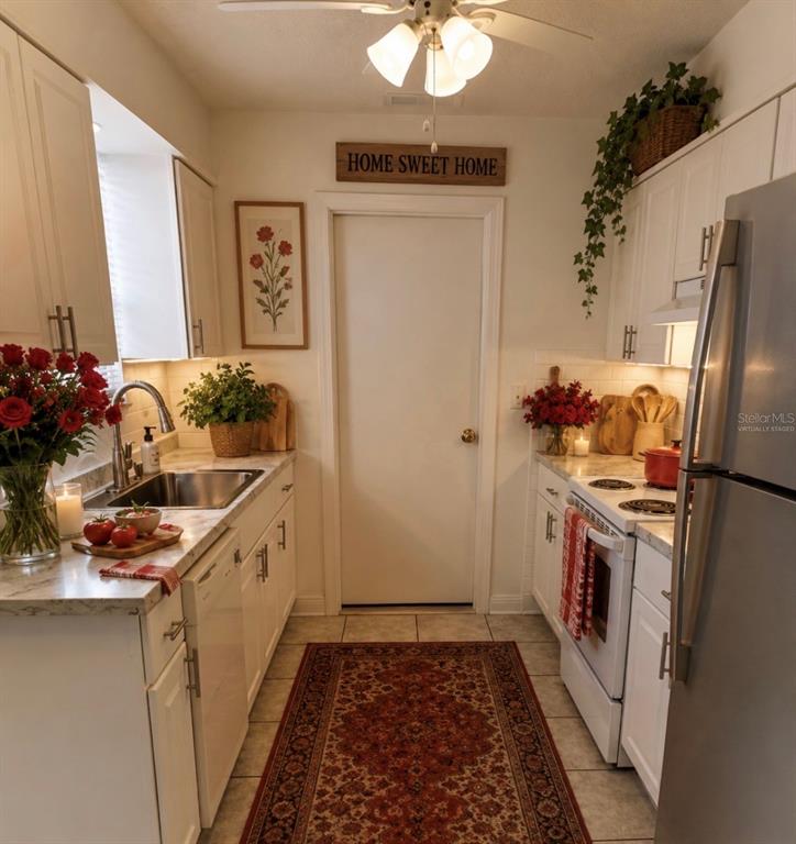 A galley kitchen features white cabinets, stainless steel appliances, a runner rug, and floral decor — 192 PONCE DE LEON DRIVE, ORMOND BEACH, FL