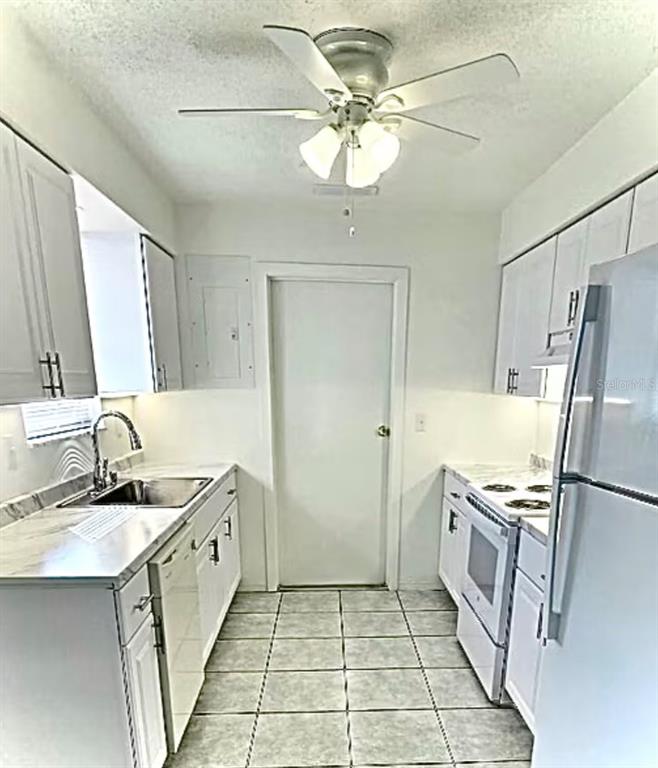 A galley kitchen features white cabinets, stainless steel appliances, and light-colored tile flooring — 192 PONCE DE LEON DRIVE, ORMOND BEACH, FL