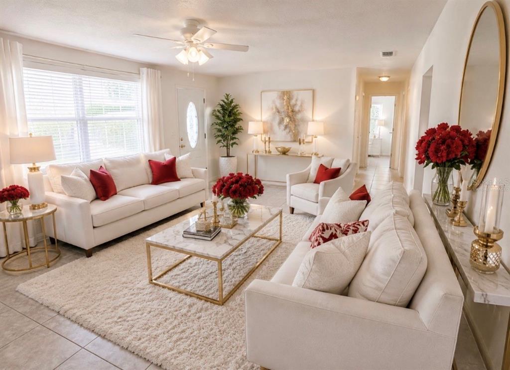 A bright living room features white sofas, a marble coffee table, and red floral accents — 192 PONCE DE LEON DRIVE, ORMOND BEACH, FL