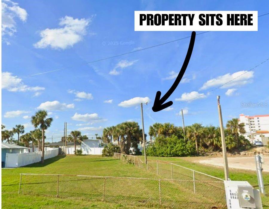 A grassy, fenced-in vacant lot features several palm trees under a bright blue sky — 3 BROOKS DRIVE, ORMOND BEACH, FL